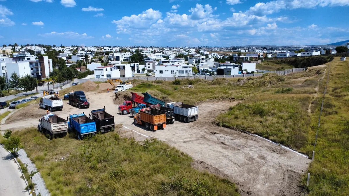 Camiones de volteo y retroexcavadoras en obra de infraestructura para fraccionamiento